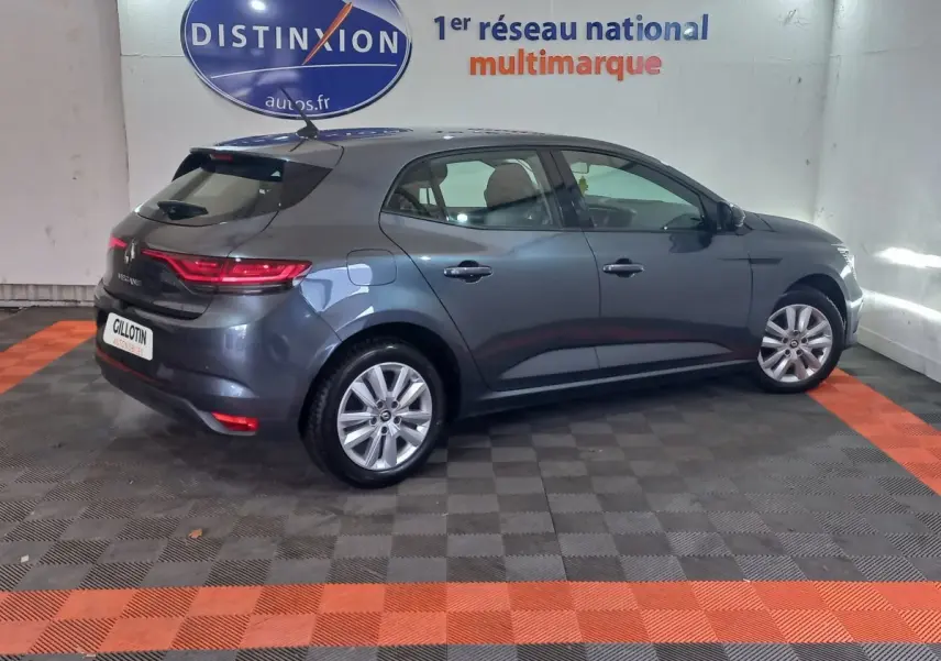 Vue 3/4 arrière droite d'une Renault Mégane Business TCe 115 gris foncé en intérieur avec feux arrière allumés.