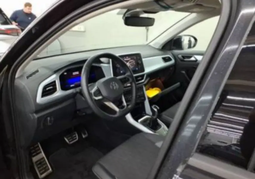 Intérieur noir du Volkswagen T-Roc 2025 vu côté conducteur, avec tableau de bord digital et écran tactile central.