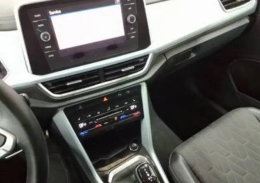 Vue intérieure du tableau de bord et console centrale du Volkswagen T-Roc 2025, avec écran tactile et sellerie tissu noir.