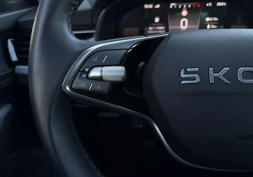 Gros plan sur le volant cuir noir de la Skoda Scala TSI 116, avec commandes multifonctions et affichage digital en arrière-plan.
