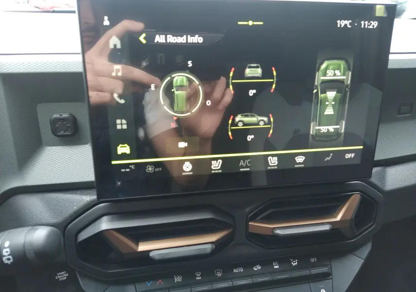 Écran tactile central du Dacia Duster Hybrid-G 150 ch, affichant les infos tout-terrain, avec aérateurs noirs et bronze en dessous.