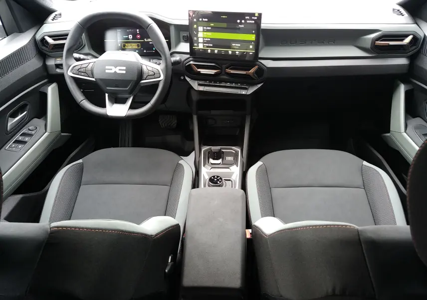 Vue intérieure avant du Dacia Duster Hybrid-G 150 ch 4x4 en finition Spirit of Sand, avec tableau de bord moderne et écran tactile central.