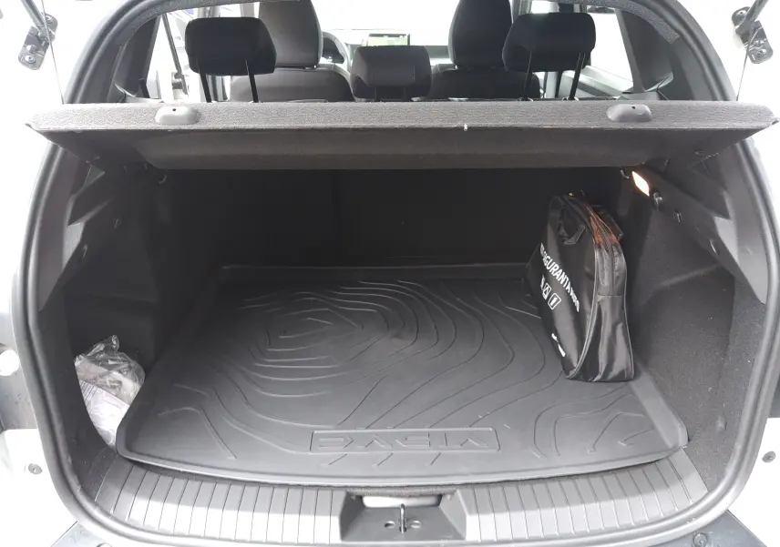 Vue arrière ouverte du coffre du Dacia Duster 2026, avec tapis de sol noir et sac de rangement visible.