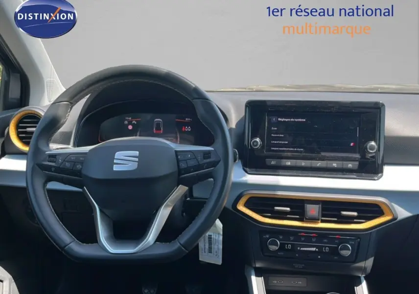 Vue intérieure centrée sur le volant et la console centrale d'une SEAT Arona gris magnetic avec inserts jaunes.