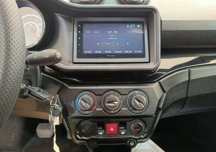 Vue intérieure centrée sur la console centrale et l’écran tactile d’une Aixam Ambition blanche, avec commandes de climatisation visibles.