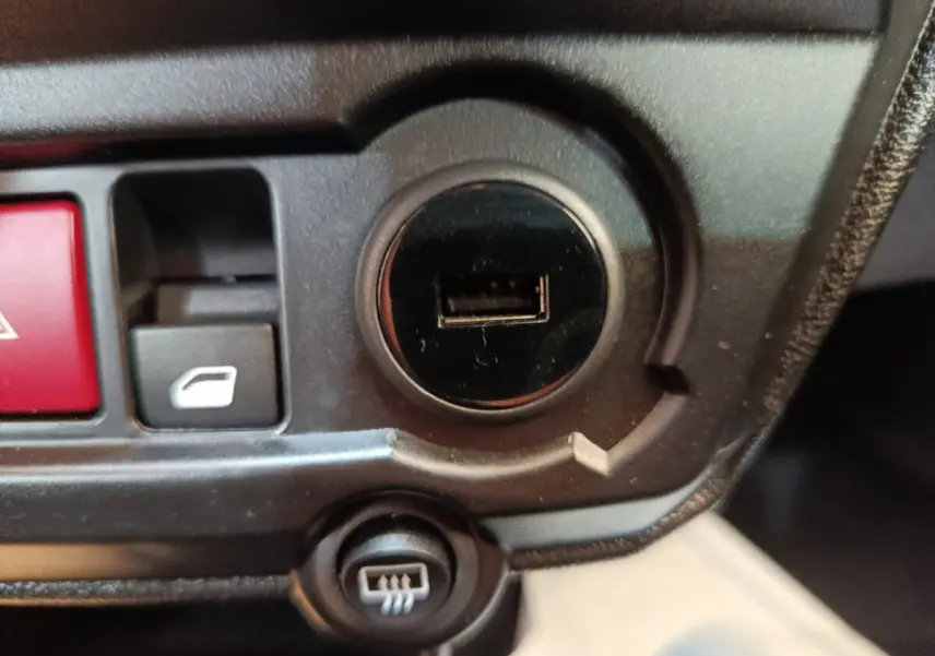 Gros plan sur la console centrale noire de l'AIXAM AMBITION 0.5 City Coupe Sport avec prise USB et boutons de commande.