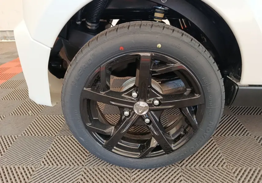 Gros plan sur la roue avant gauche avec jante noire brillante du véhicule blanc Aixam Ambition 0.5 City Coupe Sport 2026.