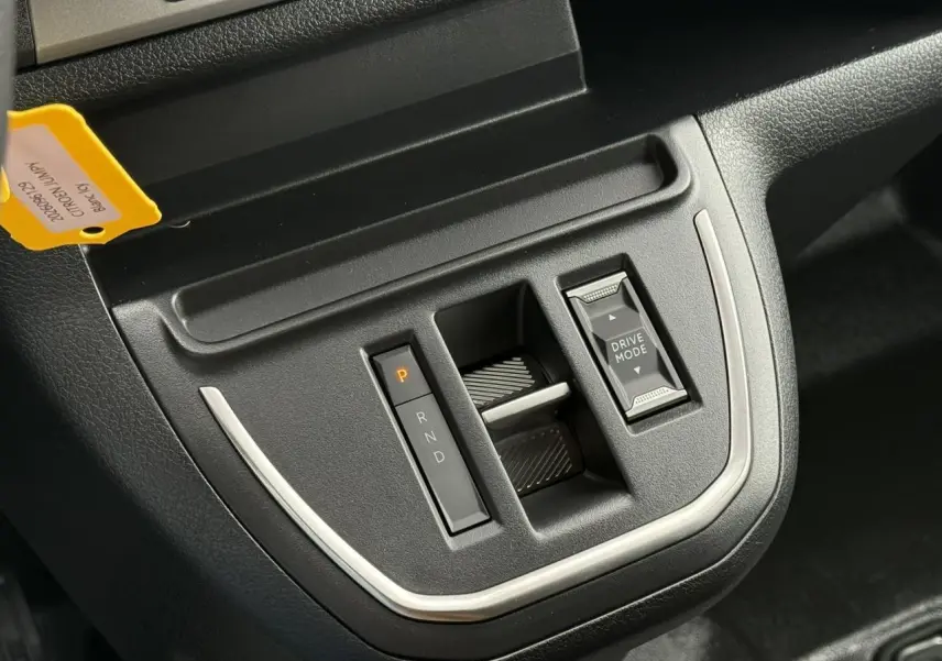 Gros plan sur la console centrale noire du Citroën Jumpy blanc Icy, mettant en valeur la commande de boîte automatique et le bouton Drive Mode.