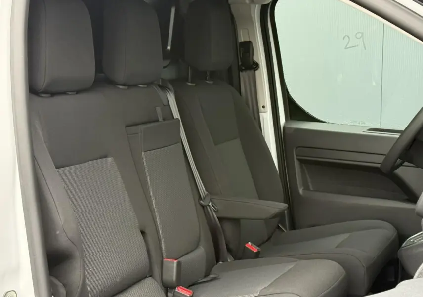 Vue intérieure côté conducteur du Citroën Jumpy blanc Icy, montrant la banquette 2 places avec siège latéral relevable.