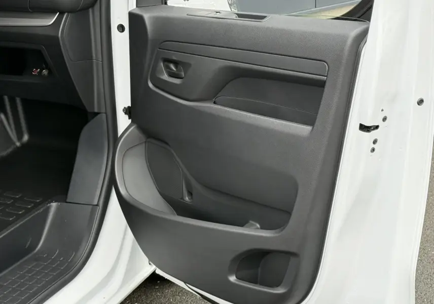 Vue rapprochée de la porte avant droite ouverte du Citroën Jumpy blanc Icy, montrant la garniture intérieure noire.