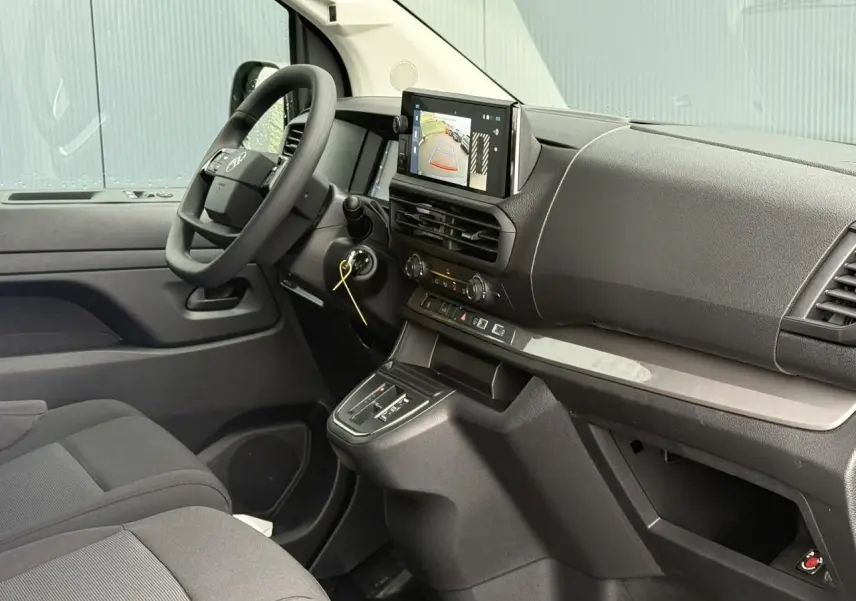 Vue intérieure côté conducteur du Citroën Jumpy blanc Icy, avec écran tactile affichant la caméra de recul et volant multifonction.