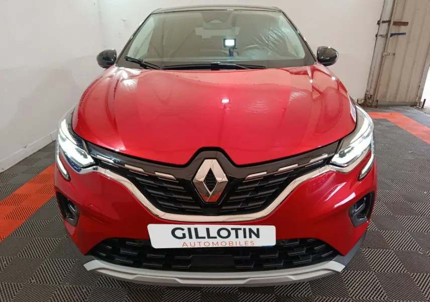 Vue frontale d'un Renault Captur Techno TCe 90 rouge 2024 avec feux LED allumés et calandre noire chromée.