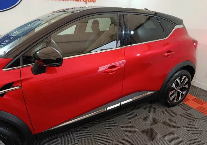 Vue latérale droite d'un Renault Captur rouge 2024 avec toit noir et jantes alliage distinctives.