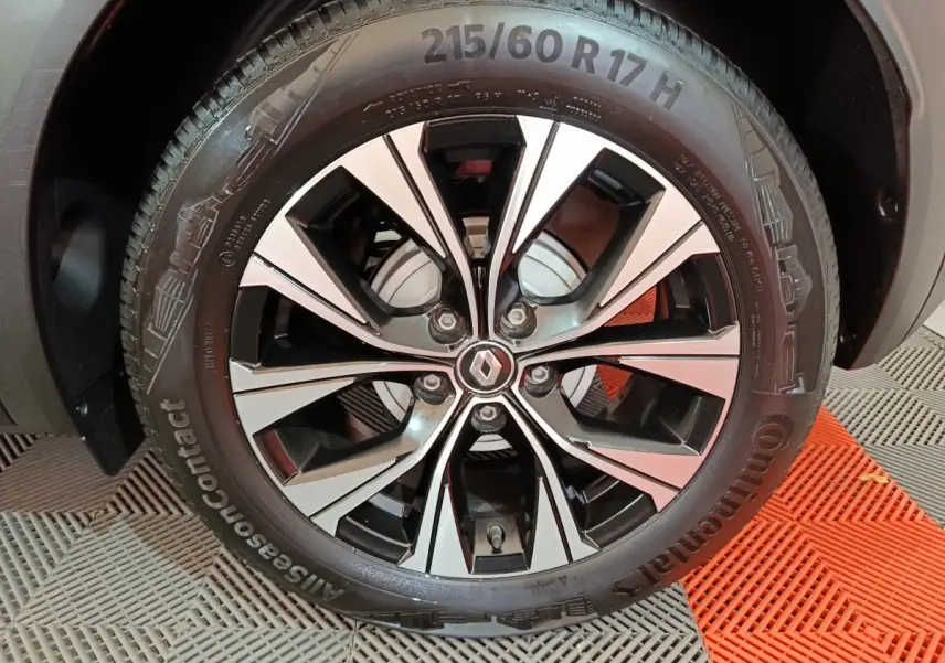 Gros plan sur la jante alliage noire et argentée avec logo Renault au centre du Renault Captur rouge 2024.