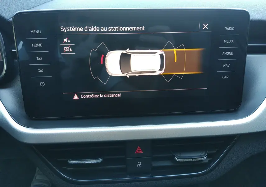 Écran central du Skoda Kamiq 2023 montrant le système d'aide au stationnement avec alertes de distance.