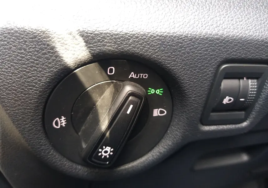 Gros plan sur le bouton de commande des phares du Skoda Kamiq 2023, avec réglage sur mode automatique et témoin vert allumé.