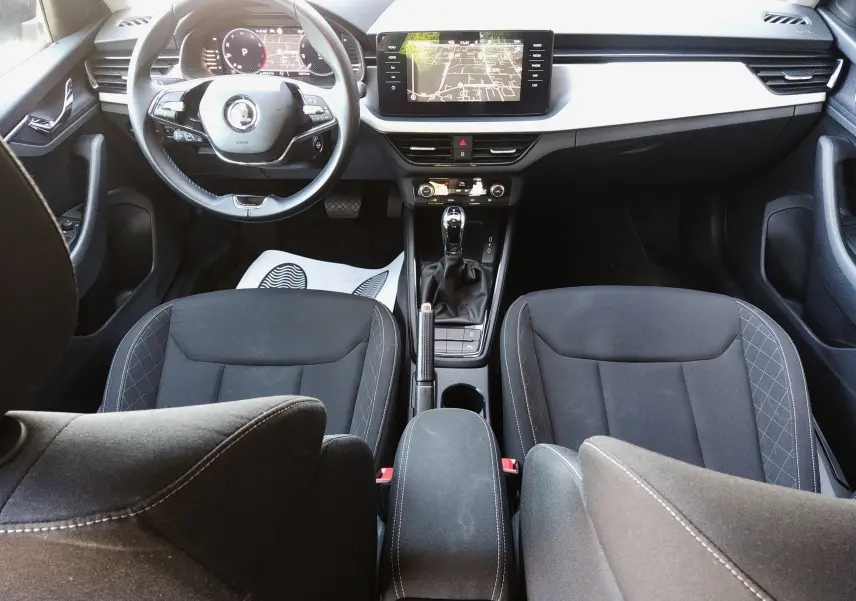 Vue intérieure avant du Skoda Kamiq 2023 gris, avec tableau de bord numérique et écran central tactile.