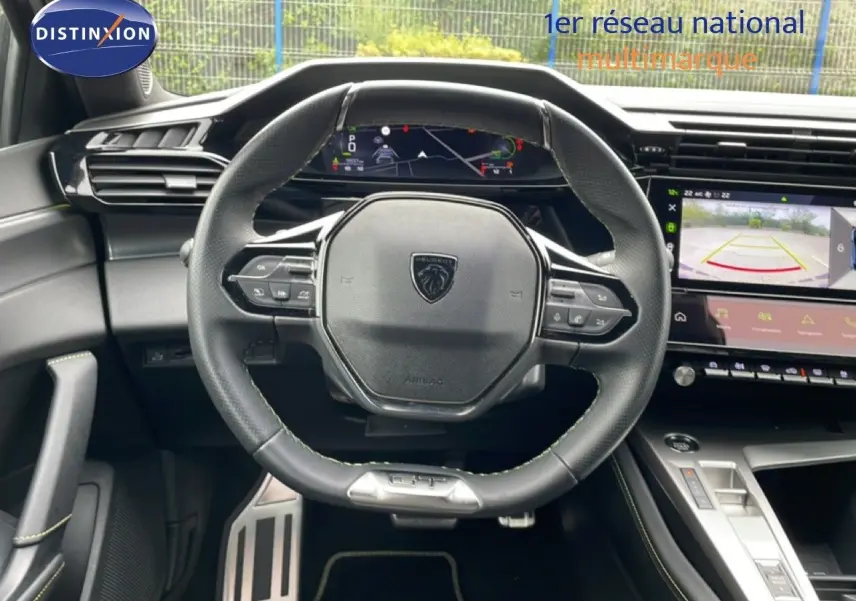 Vue intérieure centrée sur le volant cuir noir et le tableau de bord numérique du Peugeot 408 1.2 Hybrid 2025.