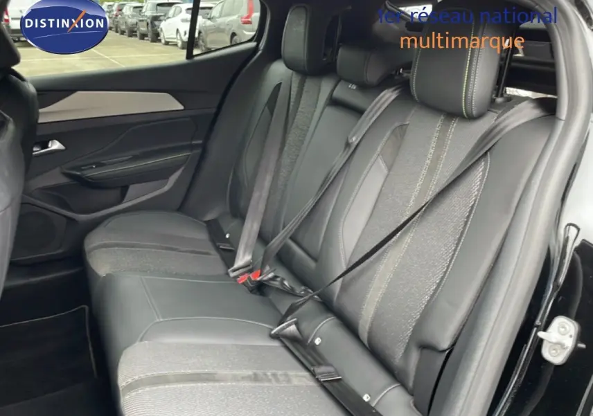 Vue latérale droite de l'intérieur arrière du Peugeot 408 noir métal, sièges mixtes cuir et tissu avec ceintures attachées.
