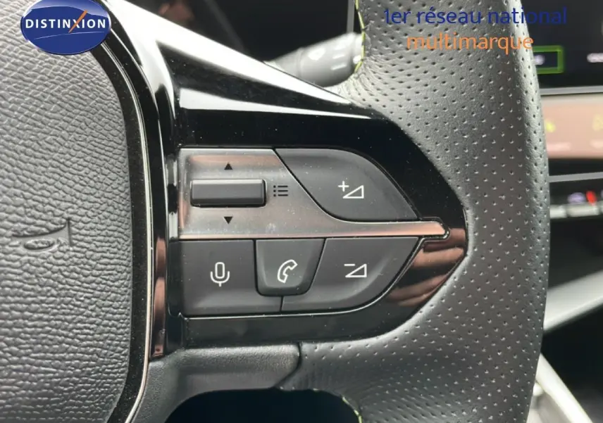 Gros plan sur les commandes au volant en cuir perforé noir de la Peugeot 408 1.2 Hybrid 2025, côté gauche.