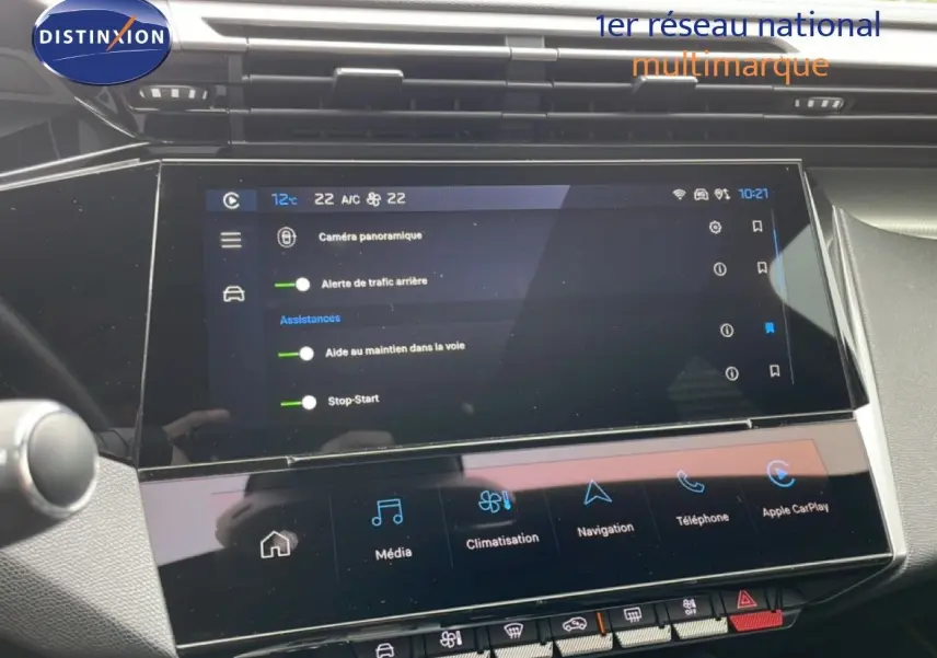 Vue rapprochée de l’écran tactile central noir du tableau de bord du Peugeot 408 1.2 Hybrid 2025, affichant les assistances et la climatisation.