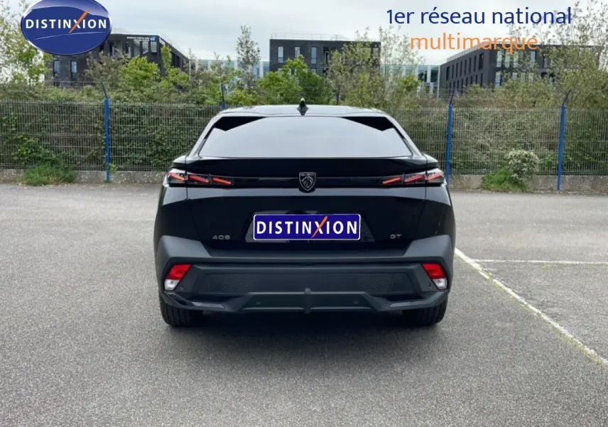 Vue arrière d'une Peugeot 408 GT noire métal 2025 avec feux LED distinctifs et logo central sur un parking.