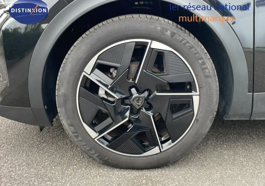 Gros plan sur la roue avant droite noire métal d'une Peugeot 408 1.2 Hybrid 145ch GT avec jante au design moderne.