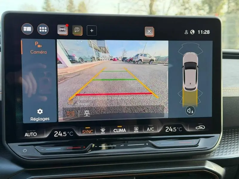 Écran tactile montrant la caméra de recul d'une SEAT LEON gris magnétique, avec affichage des lignes de guidage et température intérieure.