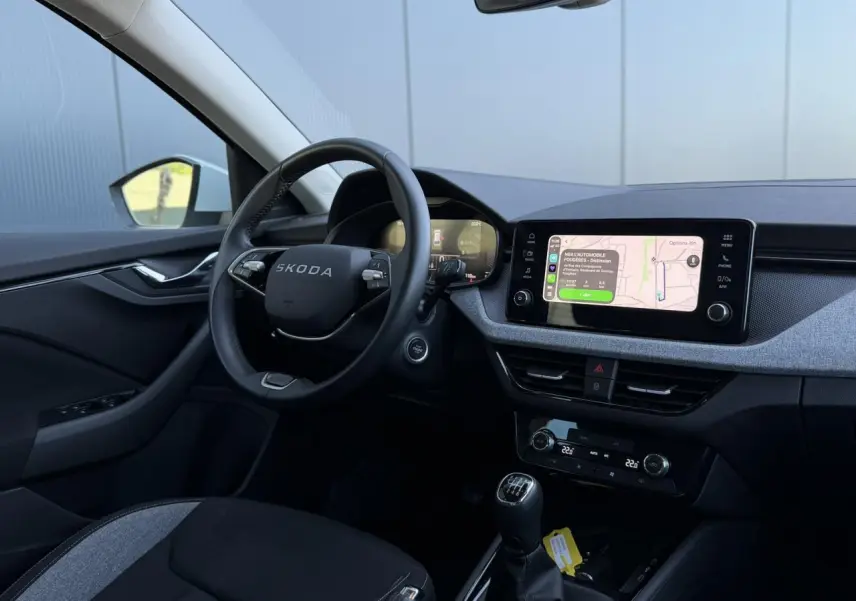 Vue intérieure côté conducteur du Skoda Scala TSI 116 blanc, avec volant cuir et écran tactile central allumé.