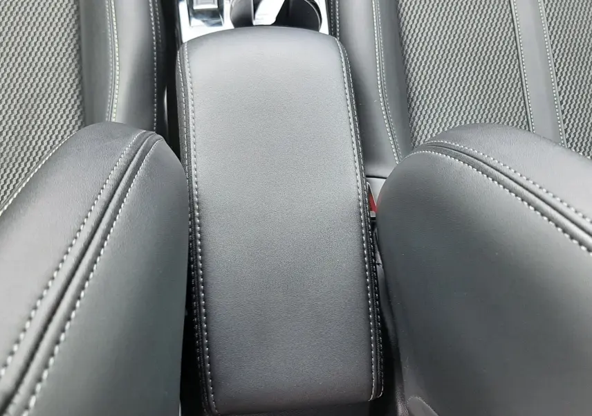 Vue plongeante sur l'accoudoir central et les sièges en cuir noir de la Peugeot 208 1.2 GT 2025.