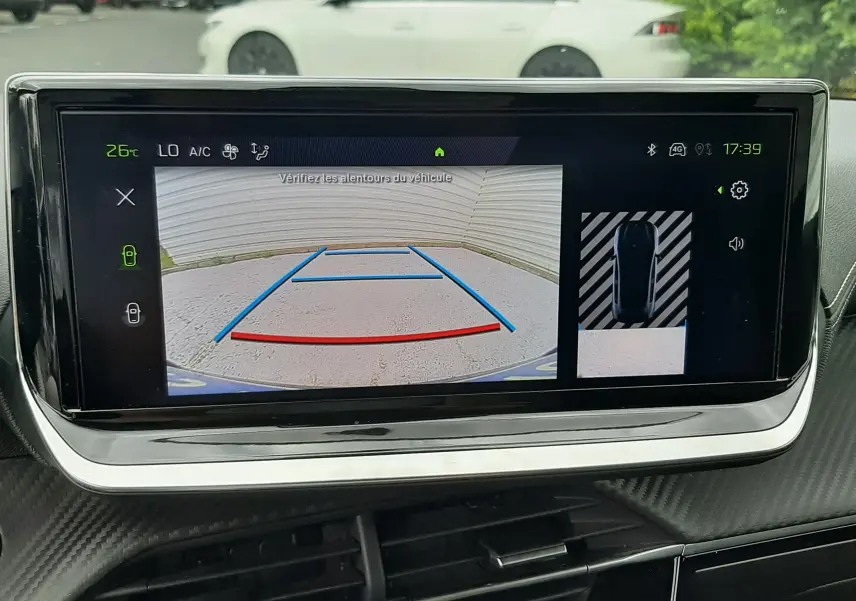 Écran de caméra de recul dans une Peugeot 208 gris Artense, vue intérieure du tableau de bord moderne.