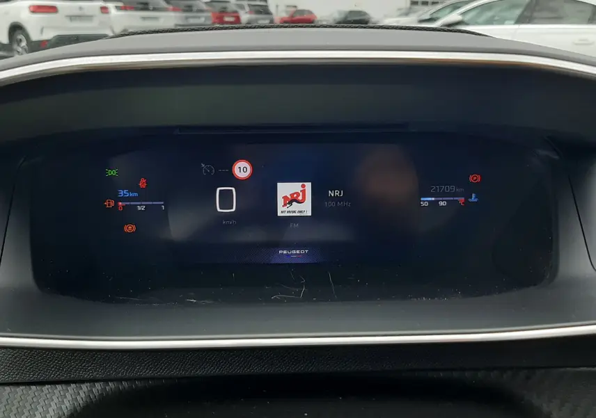 Tableau de bord numérique de Peugeot 208 1.2 100CH GT affichant la radio NRJ et les informations de conduite.