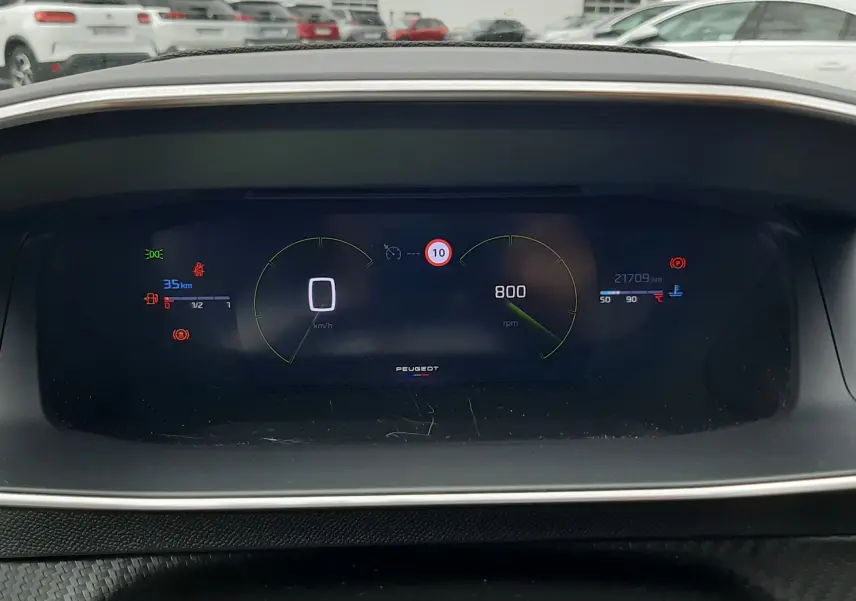 Vue rapprochée du tableau de bord numérique de la Peugeot 208 gris Artense, affichant vitesse, régime et alertes.