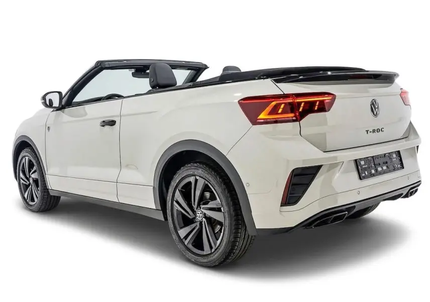 Vue 3/4 arrière droite d'un Volkswagen T-Roc Cabriolet beige métallisé avec capote ouverte et jantes noires.