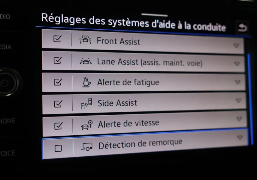Vue intérieure de l’écran tactile du Volkswagen T-Roc Cabriolet beige, affichant les réglages des aides à la conduite.