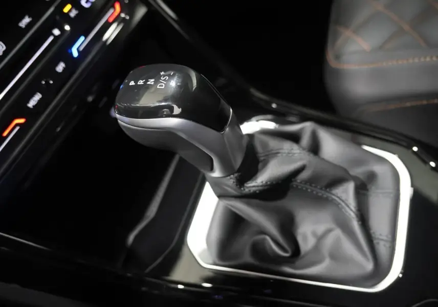 Le levier de vitesses automatique noir et argenté du Volkswagen T-Roc Cabriolet, avec coutures visibles sur le cuir environnant.