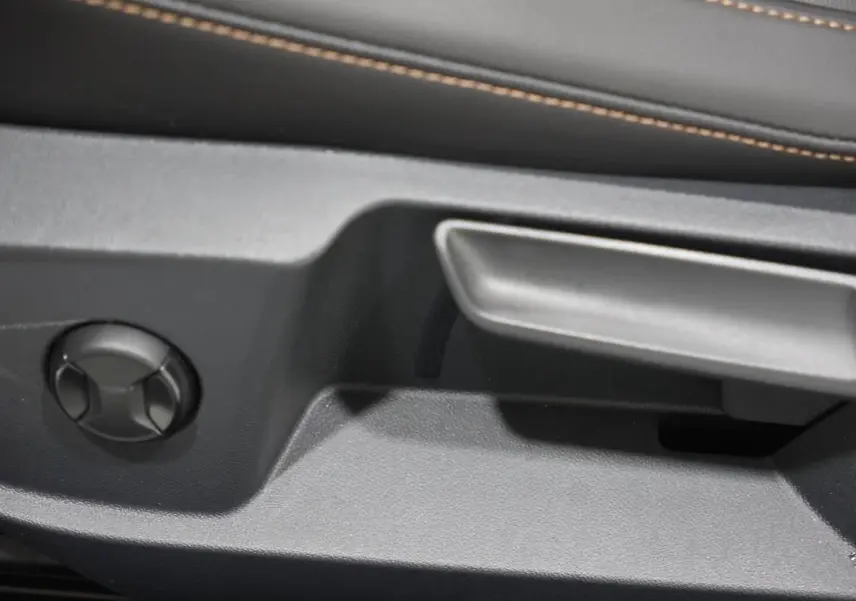 Détail de la commande de réglage manuel du siège côté gauche dans l’habitacle d’un Volkswagen T-Roc Cabriolet beige métallisé.