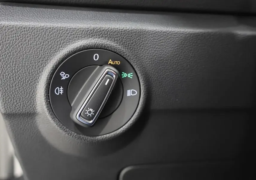 Gros plan sur le bouton de commande des phares dans l’habitacle du Volkswagen T-Roc Cabriolet beige métallisé.