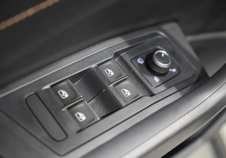 Gros plan sur les commandes de lève-vitres et réglage des rétroviseurs côté conducteur d’un Volkswagen T-Roc Cabriolet.