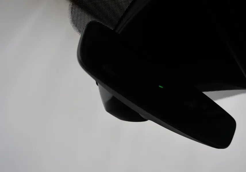 Rétroviseur intérieur noir avec témoin lumineux vert, vue rapprochée depuis l'habitacle du Volkswagen T-Roc Cabriolet beige.