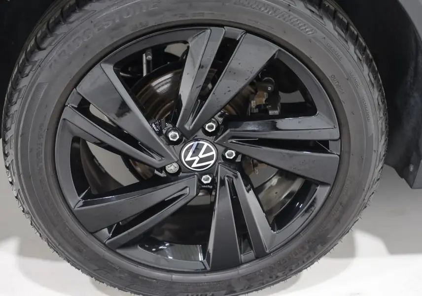 Gros plan sur la jante noire brillante avec logo Volkswagen, montée sur un pneu Bridgestone.
