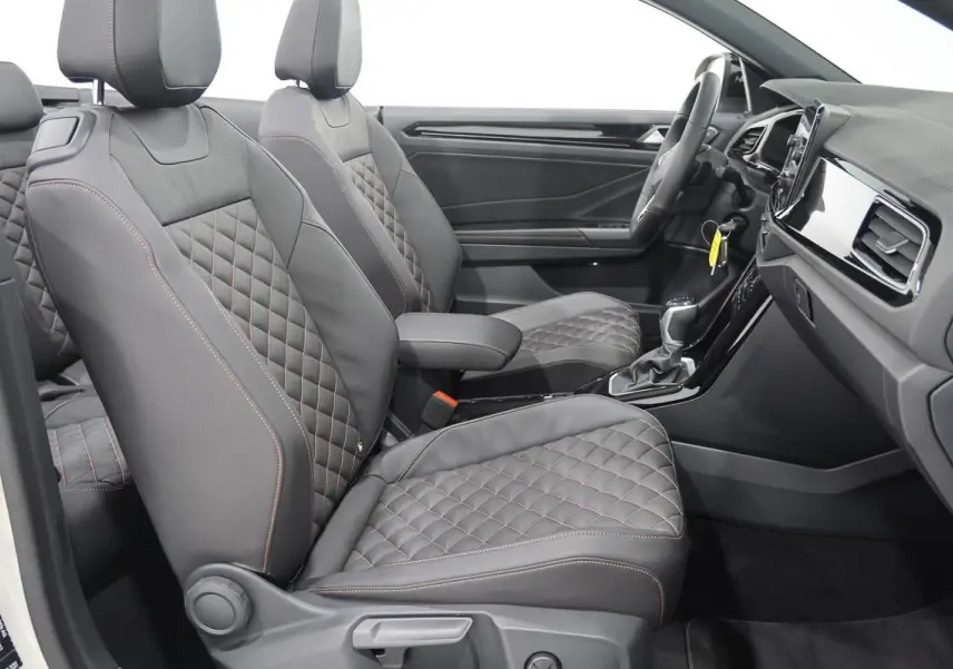 Vue intérieure côté droit du Volkswagen T-Roc Cabriolet 2025, sièges en cuir noir matelassé avec surpiqûres contrastées.