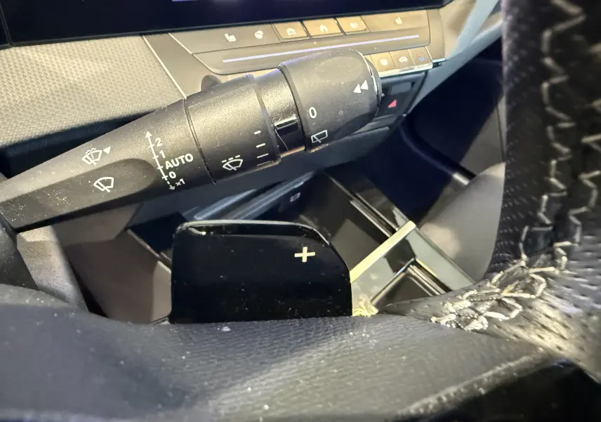 Gros plan sur le volant perforé et les commandes à gauche de l’Opel Astra Sports Tourer 2024, avec tableau de bord numérique.