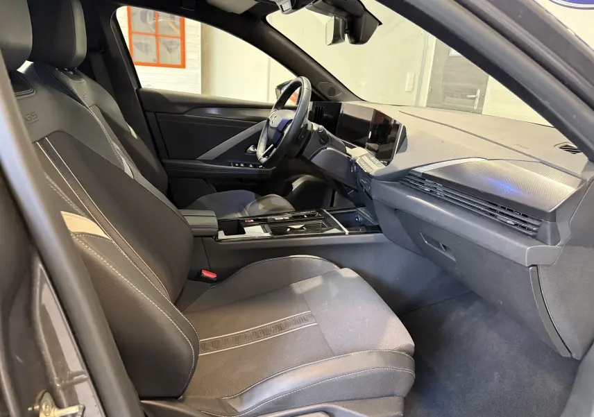 Vue intérieure côté gauche des sièges arrière noirs de l'Opel Astra Sports Tourer 2024, avec console centrale et porte ouvert.