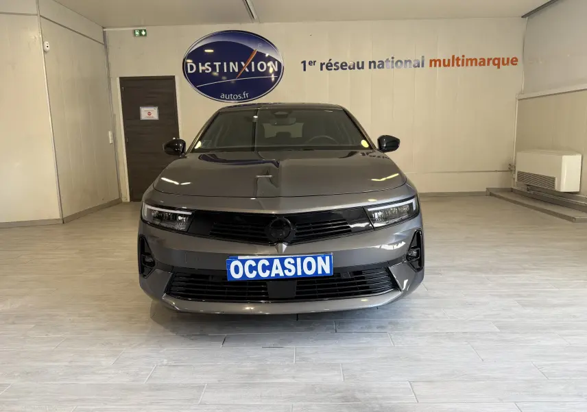 Vue frontale d'une Opel Astra Sports Tourer gris métallisé 2024 avec plaque "OCCASION" en intérieur showroom.