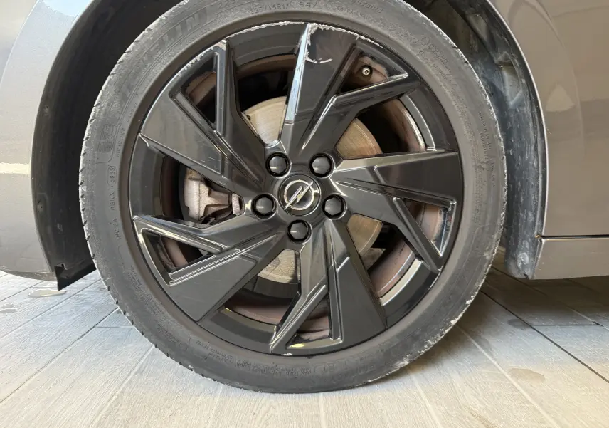 Gros plan sur la roue avant gauche de l’Opel Astra Sports Tourer gris, avec jante noire au design moderne et logo Opel central.