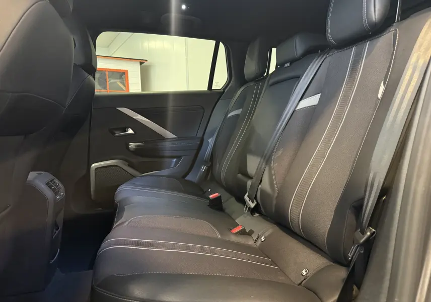 Vue intérieure côté conducteur de l'Opel Astra Sports Tourer 2024, sièges GS noirs avec surpiqûres blanches et volant cuir.