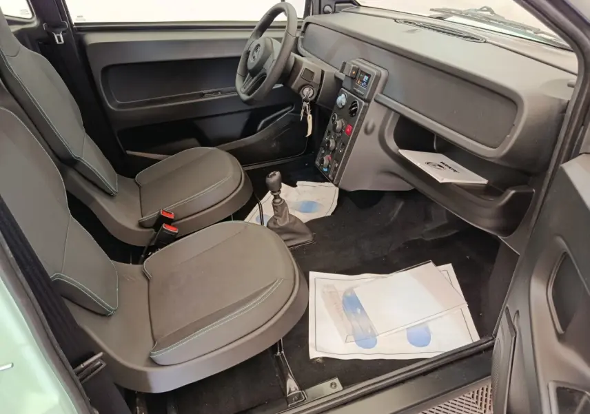 Vue intérieure côté conducteur de l'AIXAM AMBITION Easy Chic 2026, avec sièges gris et tableau de bord noir.