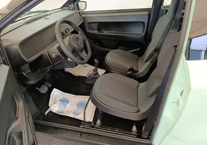 Vue intérieure côté conducteur de l'AIXAM Ambition Easy Chic 2026 vert, avec sièges gris et tableau de bord minimaliste.