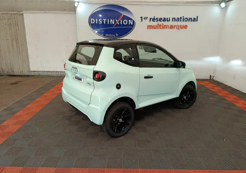 Vue 3/4 arrière droite d'une Aixam Ambition Easy Chic thermique 2026 vert clair avec toit noir et jantes noires.